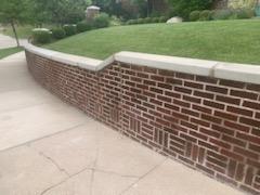 Curved brick retaining wall with a light cap beside a lawn